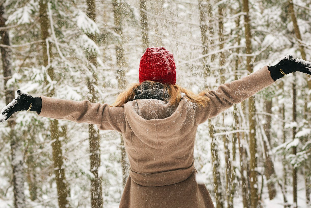 Woman in red hat enjoying a snowy winter day in Lake Placid forest.